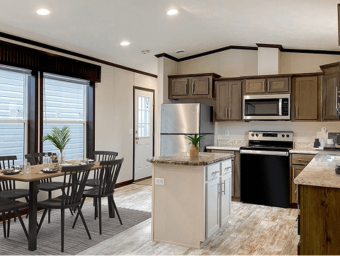 A view of a kitchen showing an island, oven, microwave and dining table.