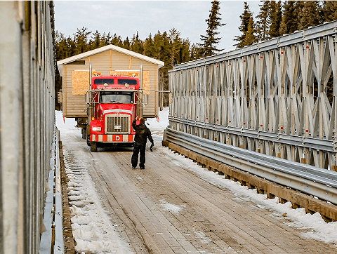 A truck preparing to move a modular home across a bridge